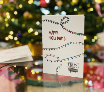 Photo of The Trust Company's holiday card with a lighted tree in the background