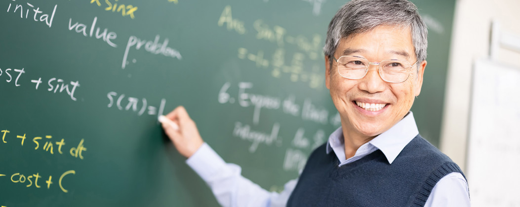 college professor doing math on chalkboard