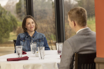 Male financial advisor shown from behind meeting with smiling female client
