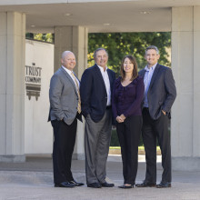 Group of four business people posed outside an office building